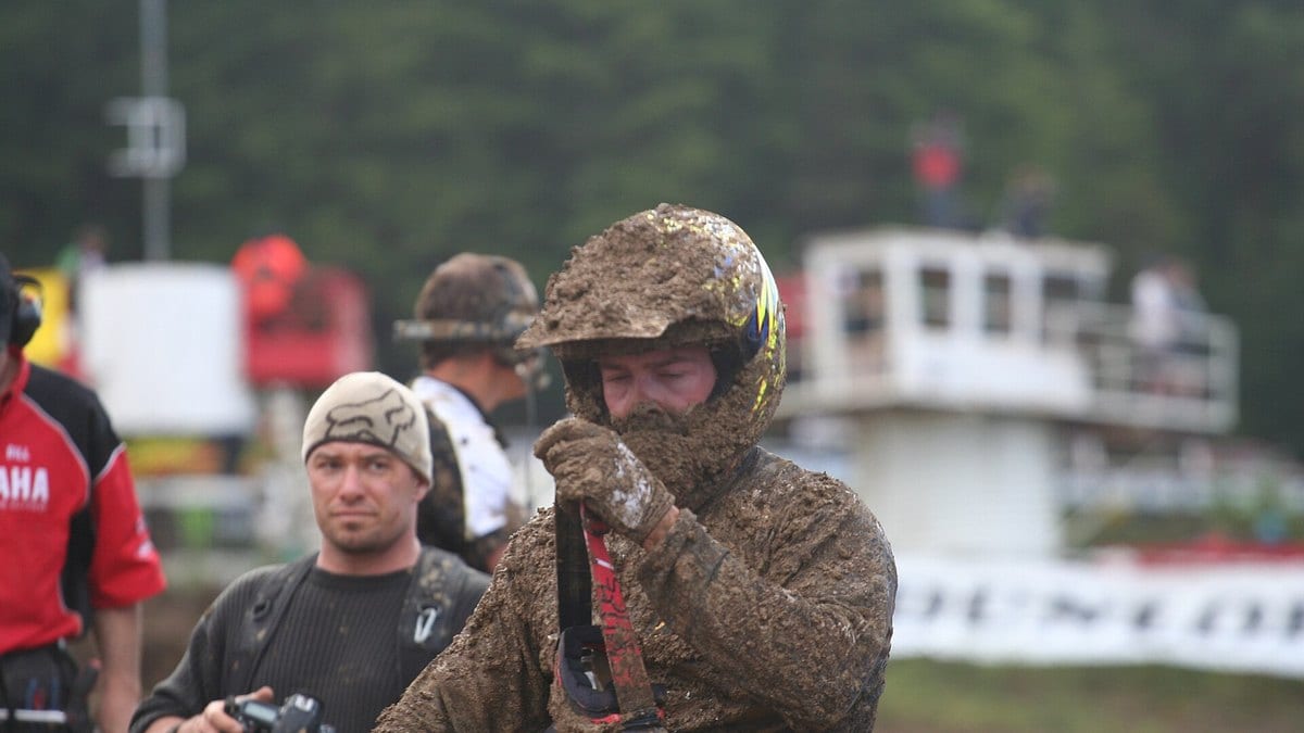 Mud-caked motocross rider adjusting goggles in the pits at the 2012 Motocross Nationals, Nanaimo